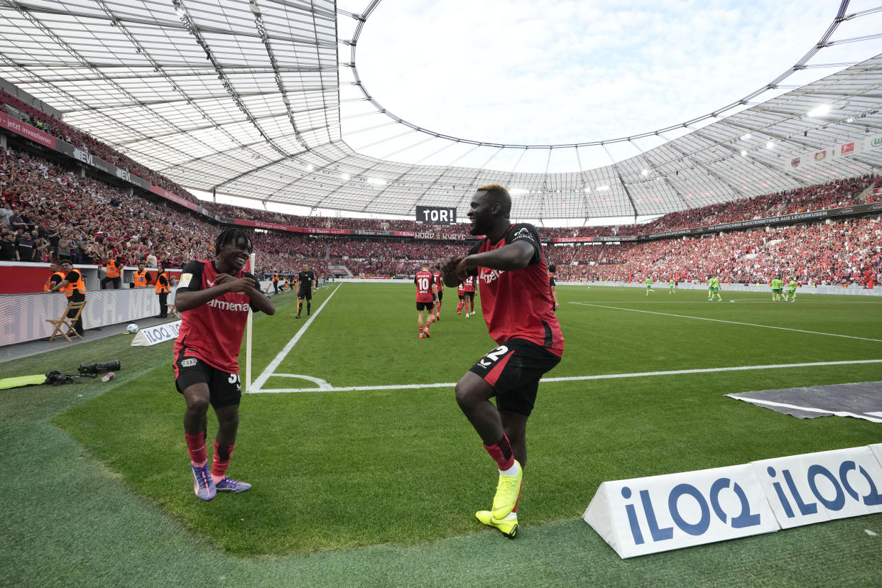 Leverkusen's Jeremie Frimpong, left, and Victor Boniface celebrate after a goal during the German Bundesliga soccer match between Bayer Leverkusen and VfL Wolfsburg at the BayArena in Leverkusen, Germany, Sunday, Sept. 22, 2024. (AP Photo/Martin Meissner)