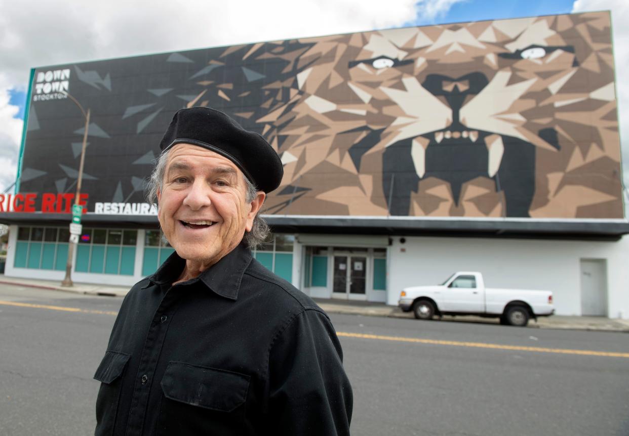 Muralist Carlos Lopez stands across the street from his latest work a 101-ft by 40-ft mural of a lion on the Price Rite Restaurant Supply building on Weber Avenue and Stanislaus Street in downtown Stockton.