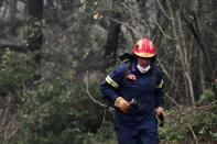 A firefighter operates in Asmini village on Evia island, about 193 kilometers (120 miles) north of Athens, Greece, Sunday, Aug. 8, 2021. Pillars of billowing smoke and ash turned the sky orange and blocked out the sun above Greece's second-largest island Sunday as a days-old wildfire devoured pristine forests and encroached on villages, triggering more evacuation alerts. (AP Photo/Michael Varaklas)