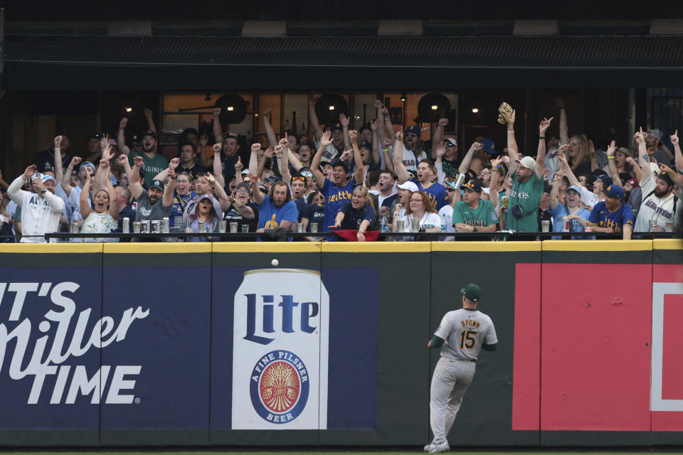 Oakland Athletics outfielder Seth Brown (15) watches as a home run ball hit by Seattle Mariners' Dylan Moore bounces back on the field during the fourth inning of a baseball game, Friday, May 10, 2024, in Seattle. (AP Photo/Jason Redmond)
