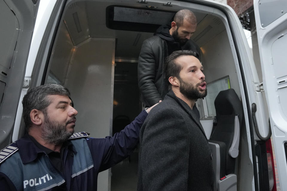 Police officers escort Andrew Tate, top, handcuffed to his brother Tristan, outside the Directorate for Investigating Organized Crime and Terrorism (DIICOT) where prosecutors examine electronic equipment confiscated during the investigation in their case, in Bucharest, Romania, Thursday, Jan. 26, 2023. Divisive influencer Andrew Tate and his brother Tristan, are held on charges of being part of an organized crime group, human trafficking and rape. (AP Photo/Andreea Alexandru)