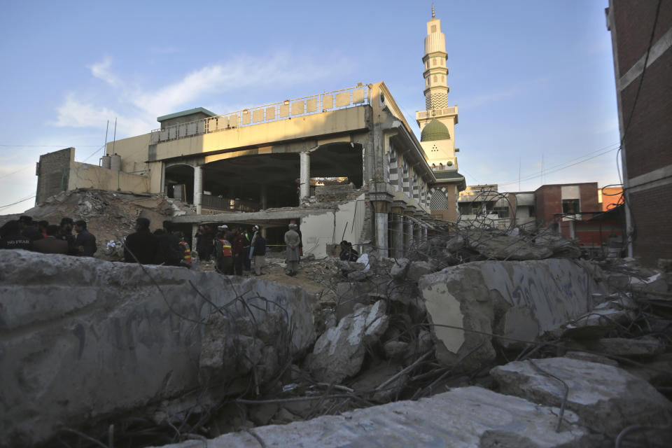 Rescue workers and people gather at the site of Monday's suicide bombing after authorities finished the rescue operation, in Peshawar, Pakistan, Tuesday, Jan. 31, 2023. A suicide bombing that struck inside a mosque at a police and government compound in northwest Pakistan reflects "security lapses," current and former officials said as the death toll from the devastating blast climbed to 100 on Tuesday. (AP Photo/Muhammad Sajjad)