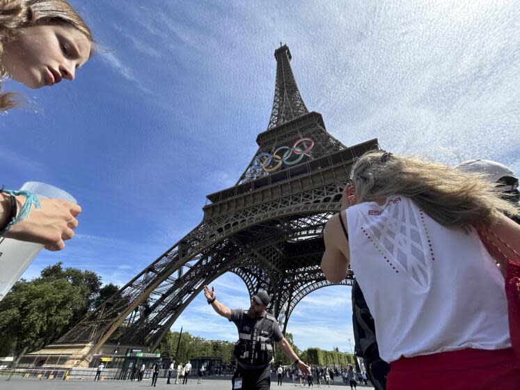 Police evacuate the area around the Eiffel Tower after a man was seen climbing the historic landmark, during the 2024 Summer Olympics, Sunday, Aug. 11, 2024, in Paris France. (AP Photo/Aijaz Rahi)