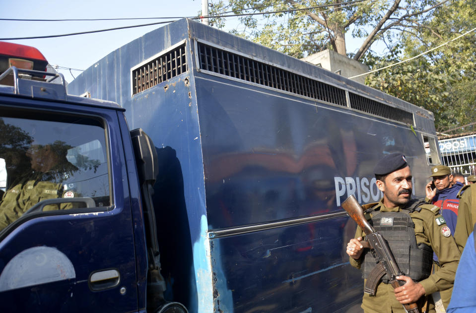 Police officers stand guard next to a van carrying some of the suspects allegedly involved in the attack and lynching of a Sri Lankan factory manager, after their appearance in anti-terrorism court, in Gujranwala, Pakistan, Monday, Dec. 6, 2021. Pakistan's prime minister told Sri Lanka's president that more than 100 people have been detained in the lynching and suspects will be "prosecuted with the full severity of the law." (AP Photo/Aftab Rizvi)