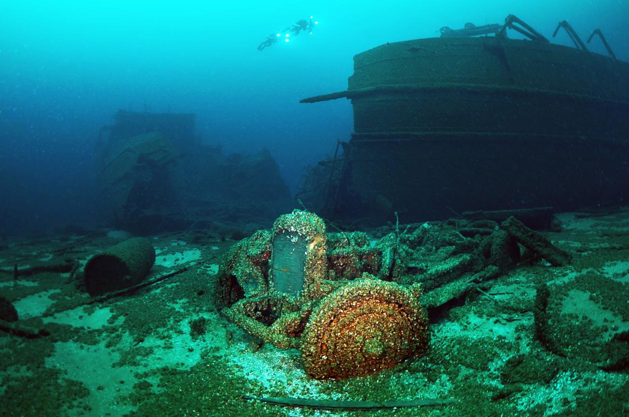 Scuba divers hover over the remains of the steamer Lakeland off Sturgeon Bay, Wisconsin in 2014. A Nash sedan, part of its cargo of Nash, Kissel and Rollins automobiles, sits on the sand next to the wreck. The Lakeland sank after it sprang a leak in 1924.