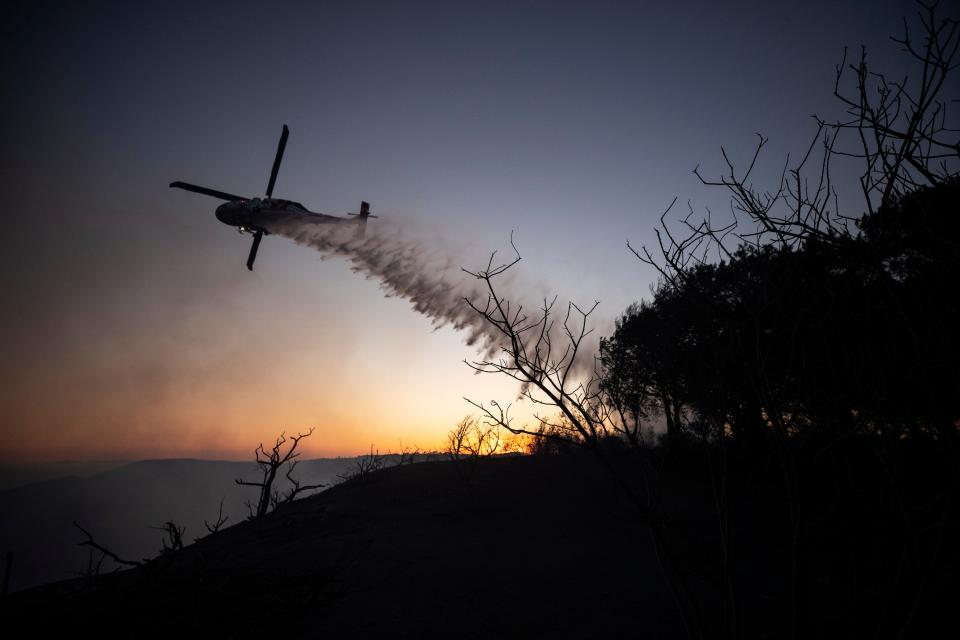 A helicoper douses the brush around the Coastal Fire in Laguna Niguel, CA (EPA)