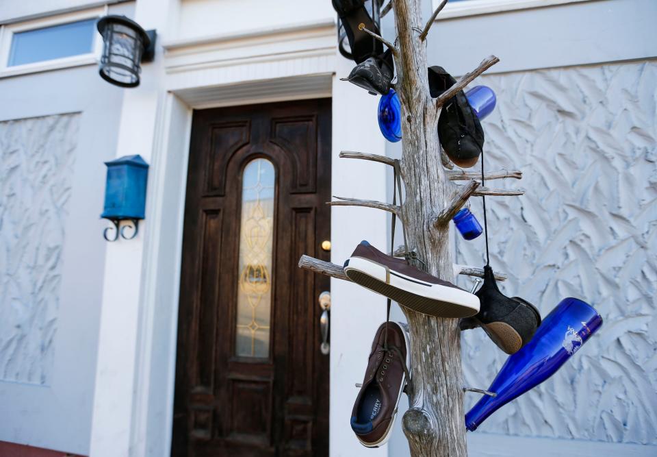 Shows and bottles hang on a dead tree outside The Shoe Tree Listening Room on East St. Louis Street on Thursday, Feb. 8, 2024.