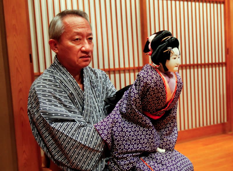 Kanjuro Kiritake, a Bunraku puppeteer, poses for a photograph in front of the drawing of his late father with a puppet in his practice room, at his house in Osaka