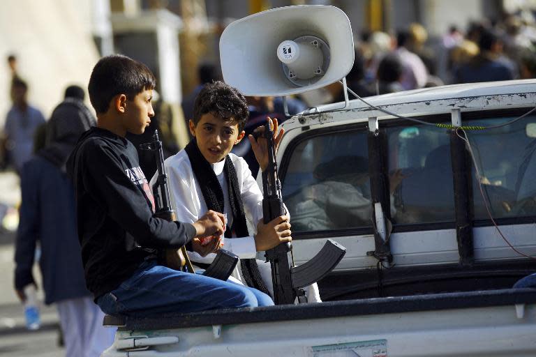 Yemeni boys hold weapons as they sit on a pick-up truck during a demonstration by supporters of the Shiite Huthi movement in Sanaa on April 22, 2015