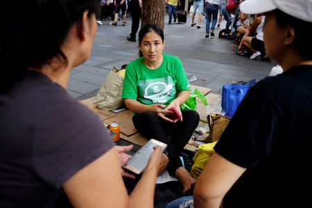 We Remit volunteer Jona de Cuia chats with a domestic helper at the financial Central district in Hong Kong, China September 2, 2018. REUTERS/Bobby Yip