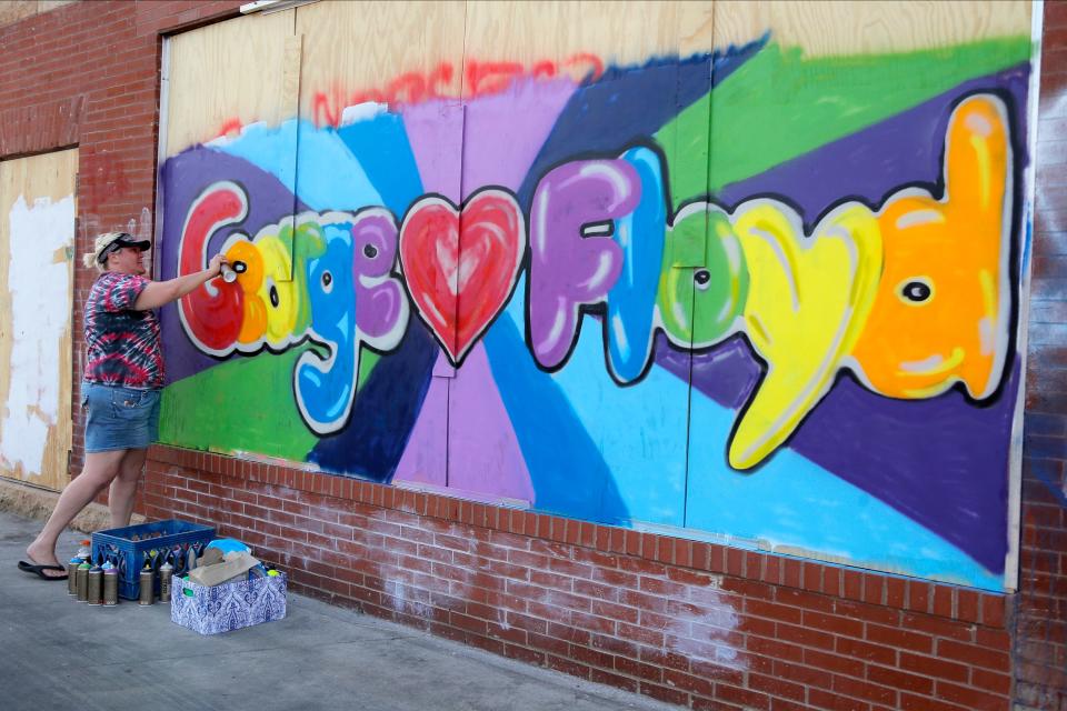A woman in June 2020 works on a mural honoring George Floyd in Minneapolis.