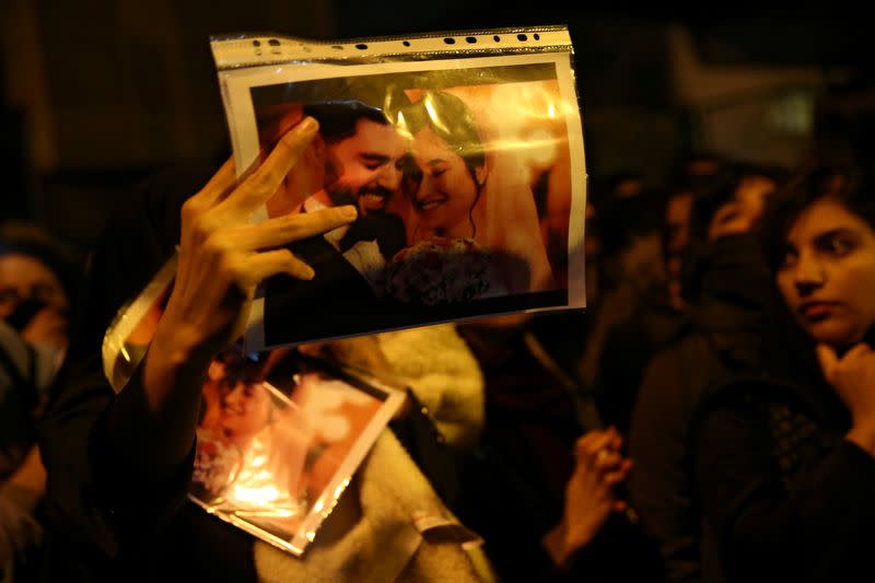 FILE PHOTO: A woman holds a picture of newlyweds, victims of the crash of the Boeing 737-800 plane, flight PS 752, as people gather to show their sympathy in Tehran