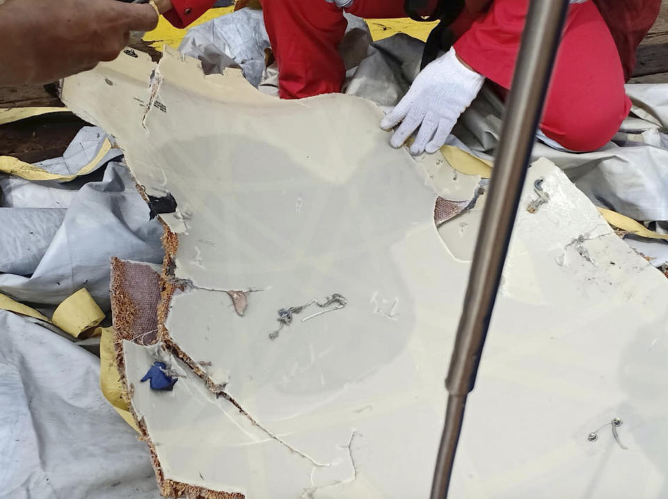 In this photo released by Indonesian Disaster Mitigation Agency (BNPB) a rescuer inspects debris believed to be from Lion Air passenger jet that crashed off West Java on Monday, Oct. 29, 2018. A Lion Air flight crashed into the sea just minutes after taking off from Indonesia's capital on Monday in a blow to the country's aviation safety record after the lifting of bans on its airlines by the European Union and U.S. (BNPB via AP)