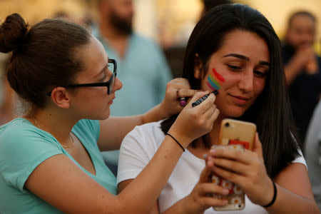 A woman paints the rainbow colours on a friend's cheek as people celebrate after the Maltese parliament voted to legalise same-sex marriage on the Roman Catholic Mediterranean island, in Valletta, Malta July 12, 2017. REUTERS/Darrin Zammit Lupi
