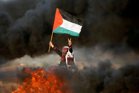 A woman waves a Palestinian flag during a protest calling for lifting the Israeli blockade on Gaza and demanding the right to return to their homeland, at the Israel-Gaza border fence east of Gaza City September 28, 2018. REUTERS/Mohammed Salem