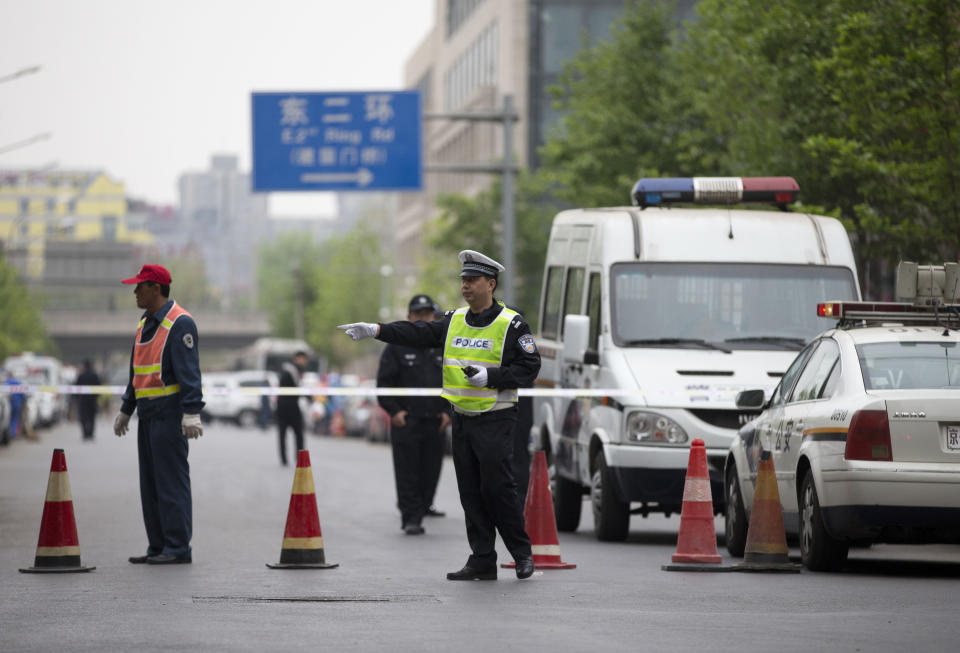 A Chinese policeman directs traffic after they closed off a road leading to the Beijing Supreme People's High Court, where Xu Zhiyong, the founder of a Chinese grassroots movement, attends his case in Beijing, China Friday, April 11, 2014. The Beijing high court on Friday upheld a guilty verdict against Xu that promoted clean governance. (AP Photo/Andy Wong)