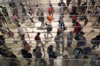 To prevent the spread of COVID-19, plexiglass keeps travelers separated as they make their way through the line to clear security at Love Field in Dallas, Friday, Dec. 31, 2021. (AP Photo/LM Otero)