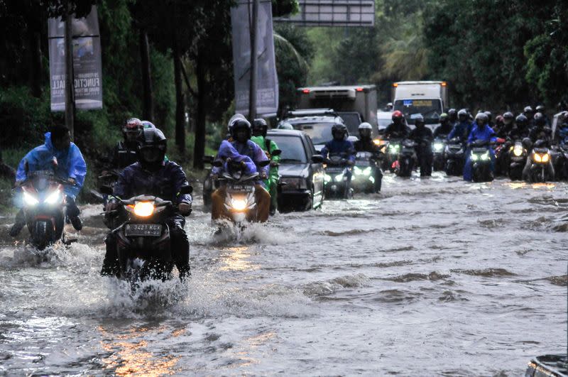 Personas en motocicleta a lo largo de una calle inundada en Bekasi, cerca de Yakarta, Indonesia 25 de febrero de 2020 en esta foto tomada por Antara Foto
