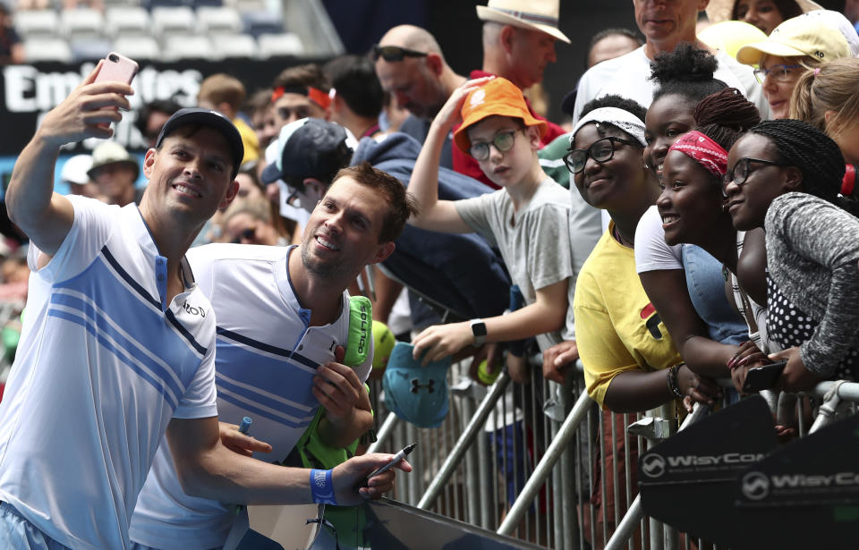 Bob, left, and Mike Bryan of the U.S. pose for a selfie with fans following their third round doubles loss to Croatia's Ivan Dodig and Slovakia's Filip Polasekd at the Australian Open tennis championship in Melbourne, Australia, Monday, Jan. 27, 2020. (AP Photo/Dita Alangkara)