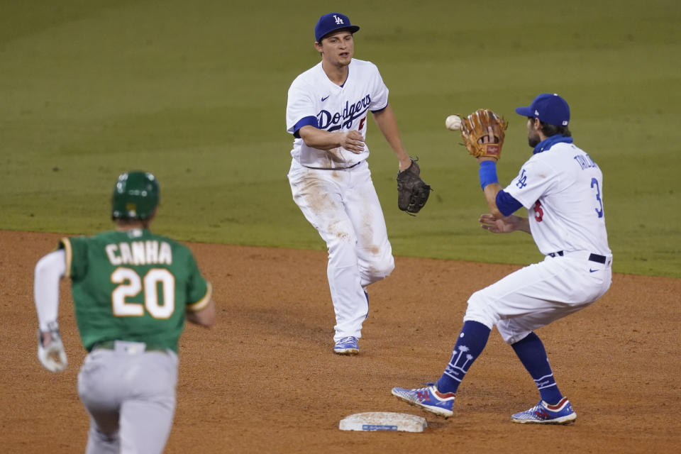 Los Angeles Dodgers shortstop Corey Seager, center, tosses the ball to second baseman Chris Taylor to put out Oakland Athletics' Mark Canha on a grounder by Jake Lamb, who was safe at first during the sixth inning of a baseball game Tuesday, Sept. 22, 2020, in Los Angeles. Lamb was safe at first. (AP Photo/Ashley Landis)