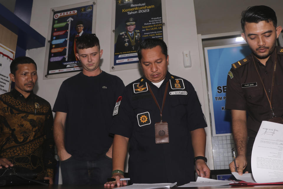 Bodhi Mani Risby-Jones from Queensland, Australia, second left, looks on as prosecutor and immigration officials sign his transfer documents at the local immigration office in Meulaboh, Aceh, Indonesia on Wednesday, June 7, 2023. The Australian surfer who was jailed for attacking several people while drunk and naked in Indonesia's deeply conservative Muslim province of Aceh will be deported back to his country after he agreed to apologize and pay compensation, officials said Wednesday. (AP Photo/Sultan Ikbal Abiyyu)
