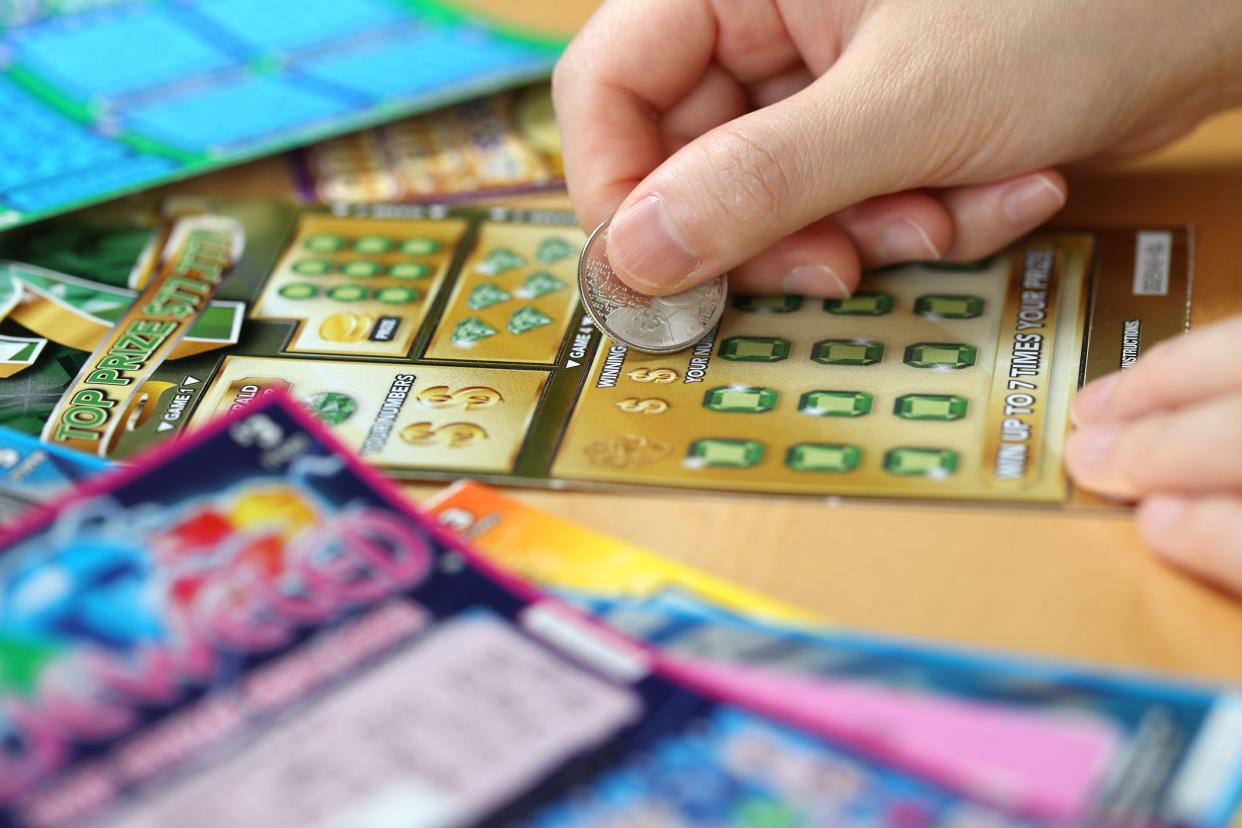 Coquitlam BC Canada - June 15, 2014 : Woman scratching lottery ticket called Monopoly. It's published by BC Lottery Corporation has provided government sanctioned lottery games.