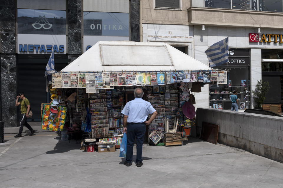 A man checks newspapers' front pages at a kiosk in Athens, on Friday, June 5, 2020. The European Commission says Greece is likely to suffer deepest recession in the eurozone this year, but first quarter growth figures were better than expected. (AP Photo/Yorgos Karahalis)
