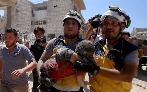 Members of the Syrian civil defence, known as the White Helmets, pull out an injured but alive child from under the rubble following a Russian air strike on Maaret al-Numan - Credit: AFP