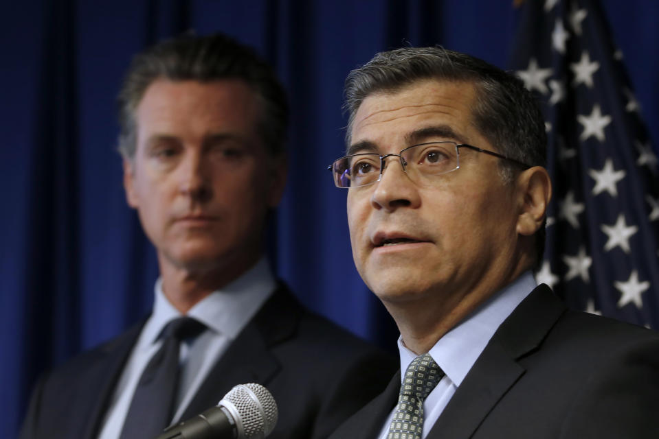 FILE - In this Sept. 18, 2019, file photo California Attorney General Xavier Becerra, right, speaks next to Gov. Gavin Newsom during a news conference in Sacramento, Calif. Newsom requested Monday, Oct. 21, 2019, that state Becerra investigate whether the retail gasoline industry is engaging in false advertising or price fixing to charge drivers more at the pump. (AP Photo/Rich Pedroncelli, File)