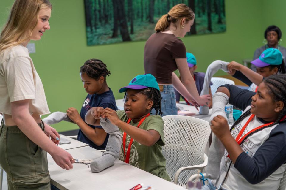 Girl Scout Zoe Granger, left, helps Girl Scouts from Detroit and Downriver as they fill socks with needed supplies for homeless people using the Caring Kids Kits she created at the Girl Scouts of Southeastern Michigan's Detroit Service Center in Detroit on Wednesday, Aug. 16, 2023.