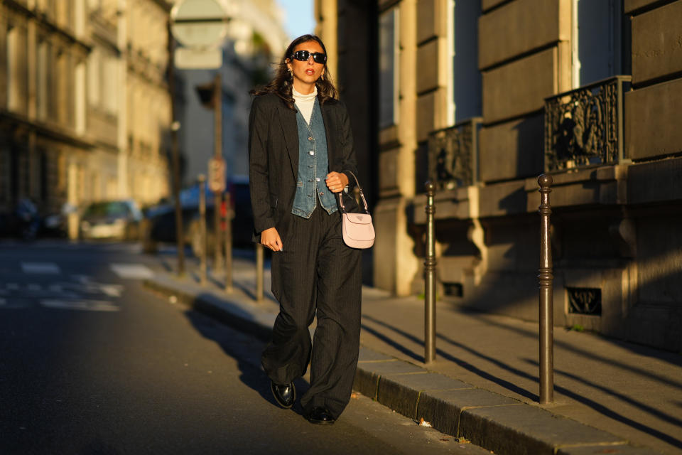 woman in white turtleneck, denim vest, and a black suit