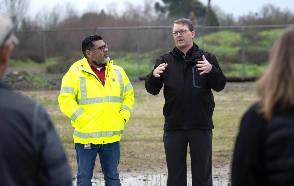 Nathan Houx, manager of park planning and development for the city of Modesto, right, and Jason Ortega, senior landscape architect, left, talk with group of local and state officials during a tour the new boat ramp at Tuolumne River Regional Park in Modesto, Calif., Wednesday, Feb. 7, 2024.