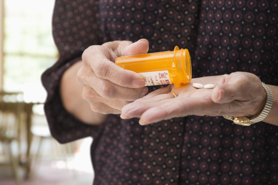 Woman pouring out pills from medicine bottle