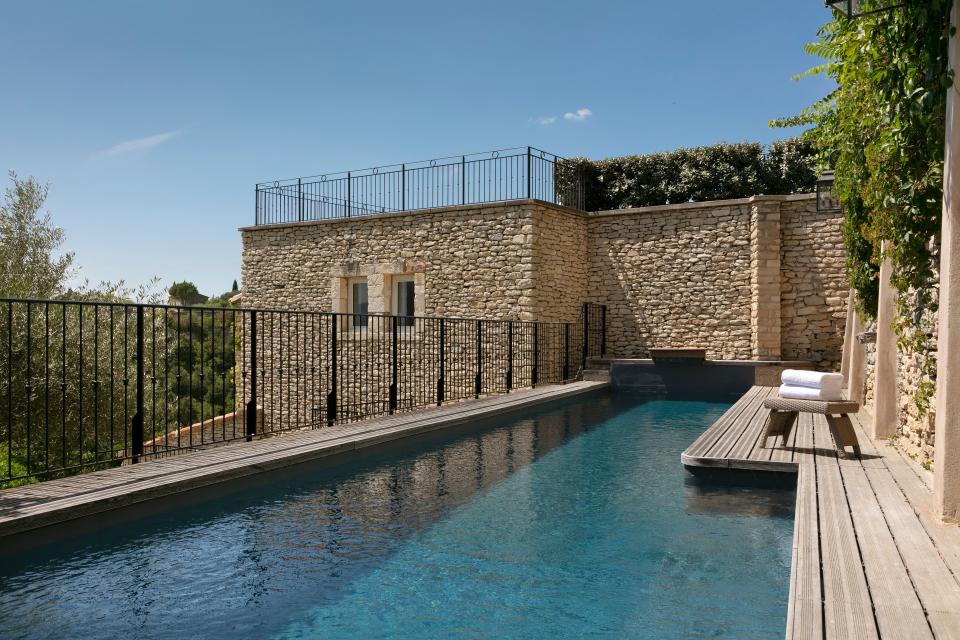 A pool at Airelles Gordes in La Bastide overlooking olive groves and cypress trees.