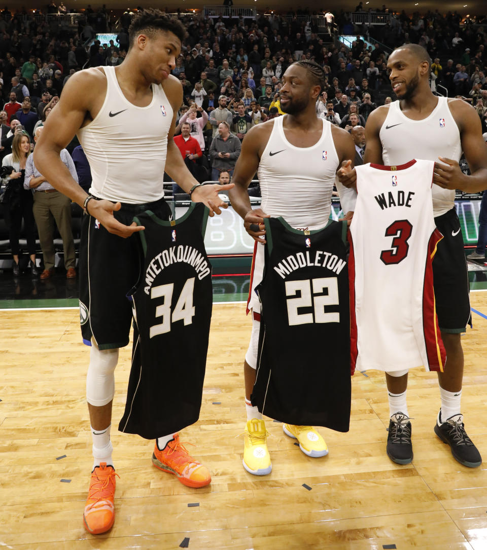 Milwaukee Bucks' Giannis Antetokounmpo, left, and Khris Middleton, right, swap jerseys with Miami Heat's Dwyane Wade after an NBA basketball game Friday, March 22, 2019, in Milwaukee. (AP Photo/Jeffrey Phelps)