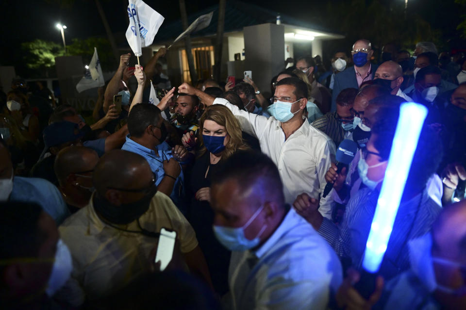 Pedro Pierluisi, gubernatorial candidate with the New Progressive Party (PNP), arrives at Vivo Beach Club accompanied by resident commissioner Jennifer Gonzalez to celebrate a slim lead of the pro-statehood party in the Puerto Rican general elections, in Carolina, Puerto Rico, Tuesday, Nov. 3, 2020. Pierluisi briefly served as governor following last year's massive protests that led to the resignation of former Gov. Ricardo Rosselló. (AP Photo/Carlos Giusti)