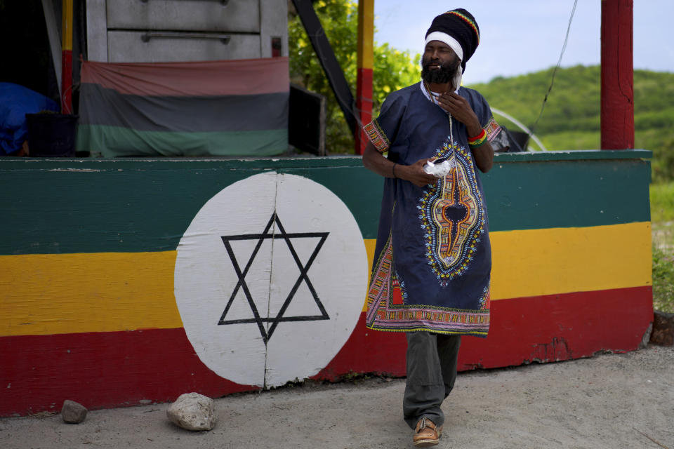 Ras Tashi, a priest, and member of the Ras Freeman Foundation for the Unification of Rastafari, puts on his late mother's robes and smokes a joint as he prepares for service in the tabernacle on Sunday, May 14, 2023, in Liberta, Antigua. (AP Photo/Jessie Wardarski)