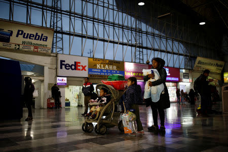 Honduran migrant Erly Marcial, 21, carries her newborn son Alvin with her children, Maria, 6, and David, 2, while her husband Alvin Reyes buys bus tickets to Mexico City, at a bus station in Puebla, Mexico, November 13, 2018. REUTERS/Carlos Garcia Rawlins