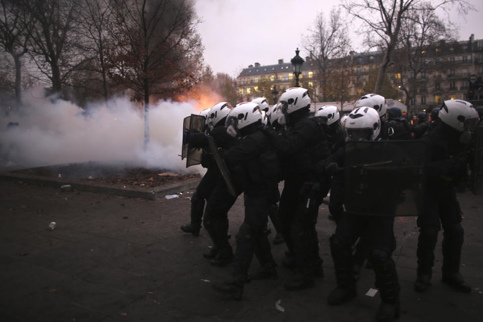 Riot police officers advance during a demonstration in Paris, Thursday, Dec. 5, 2019. Small groups of protesters are smashing store windows, setting fires and hurling flares in eastern Paris amid mass strikes over the government's retirement reform. (AP Photo/Rafael Yaghobzadeh)