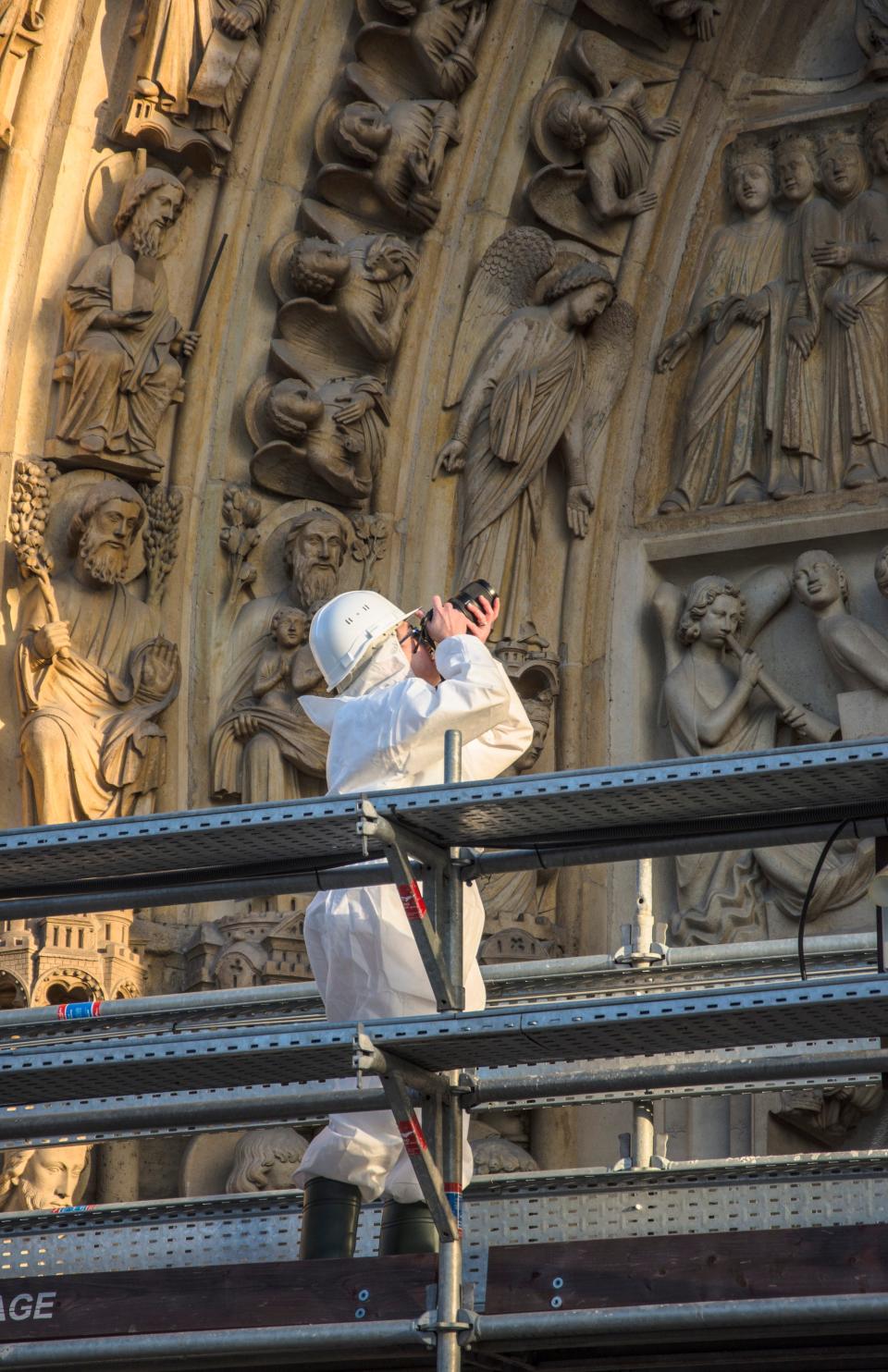 Jennifer Feltman works on the main entrance on the west facade of Notre Dame Cathedral where she is helping document and study the sculptures on the exterior of the famous cathedral as restoration work continues from the 2019 fire. 