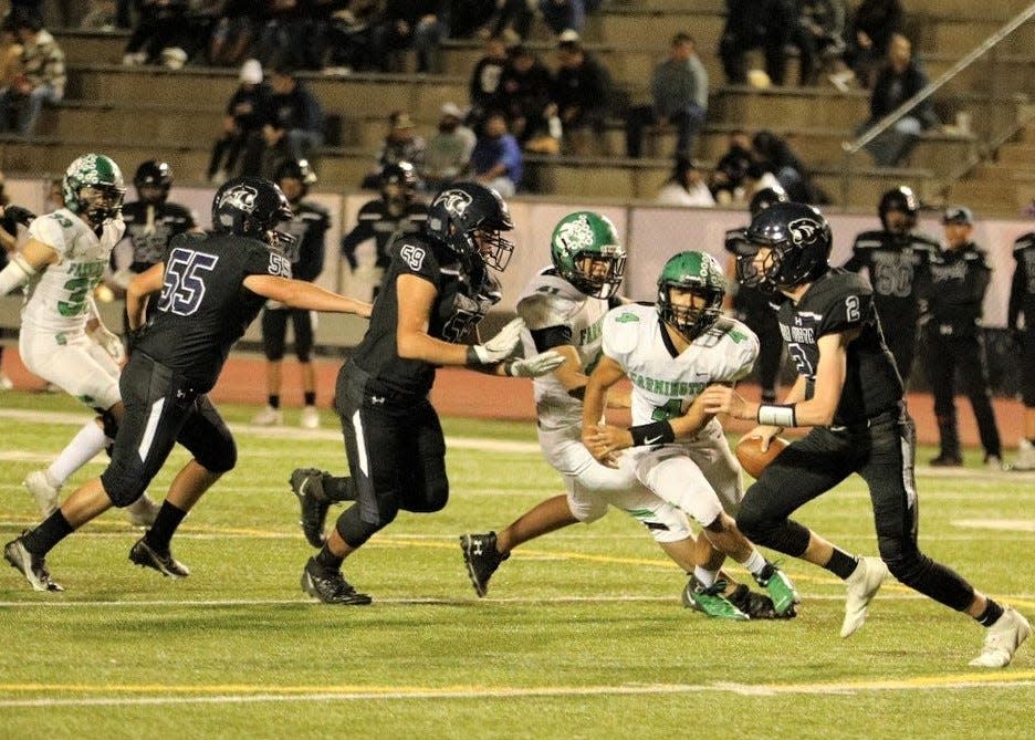 Piedra Vista quarterback Logan Howell (2) is chased out of the pocket by Farmington defensive lineman Christian Baca (4) during a game, Friday, Oct. 29, 2021 at Hutchison Stadium.