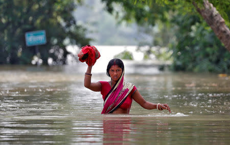 A woman wades through a flooded village in Bihar, India August 22, 2017. REUTERS/Cathal McNaughton