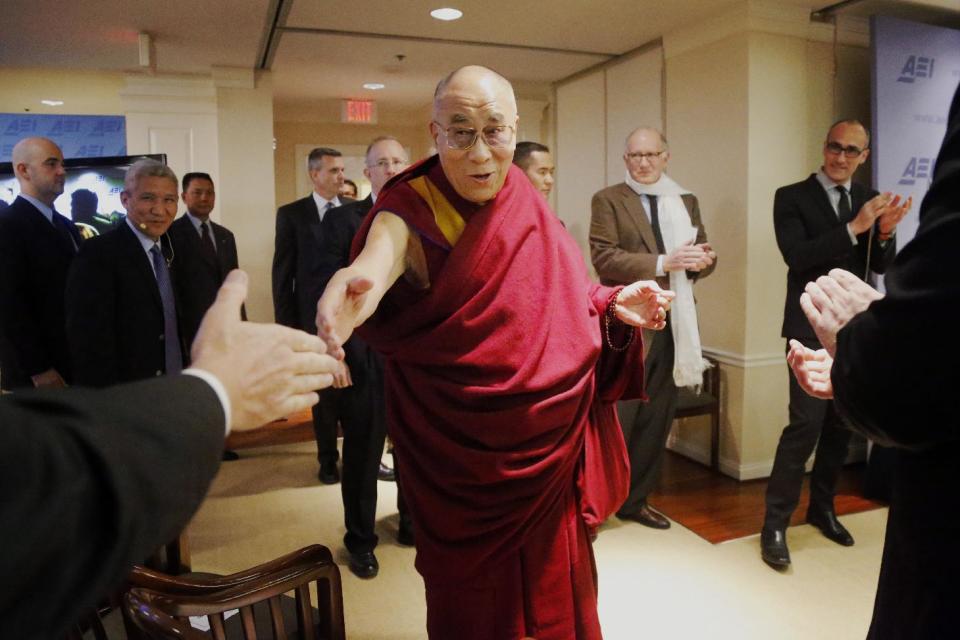 Tibetan spiritual leader the Dalai Lama greets audience members as he arrives to speak at an event entitled: "Happiness, Free Enterprise, and Human Flourishing" Thursday, Feb. 20, 2014, at the American Enterprise Institute in Washington. (AP Photo/Charles Dharapak)