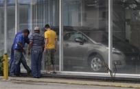 Men look at the price of Peugeot cars in Havana January 3, 2014. REUTERS/Enrique de la Osa