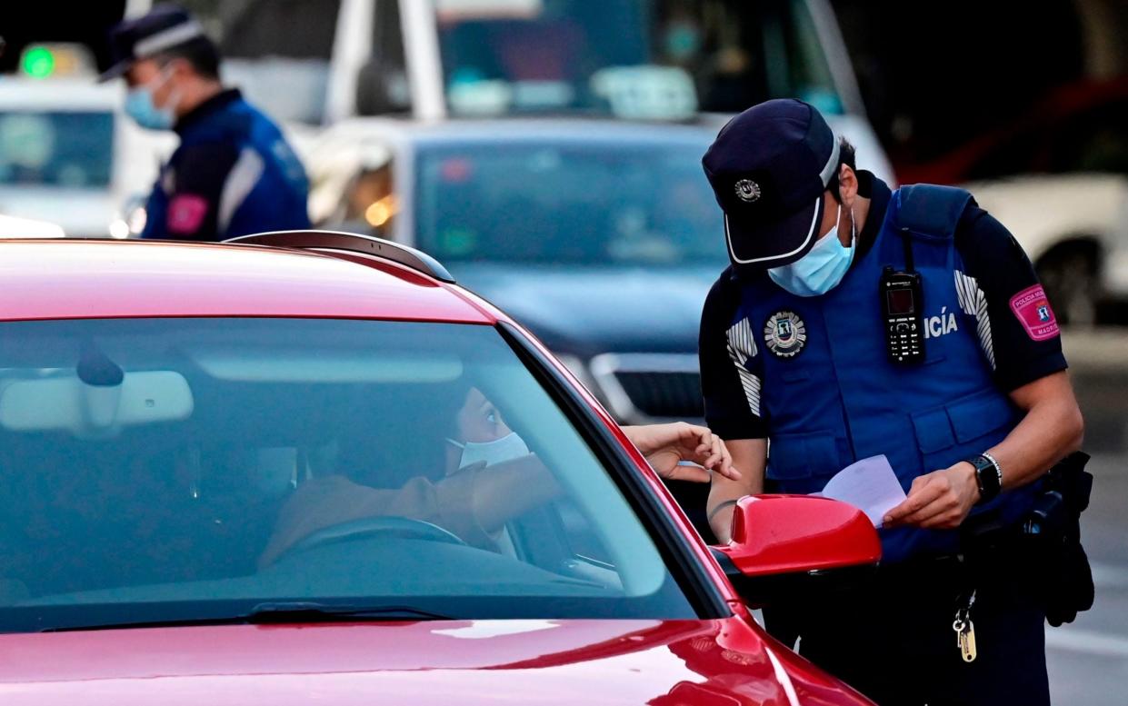 Local police monitor people's movements at a traffic checkpoint in the Puente de Vallecas neighbourhood - AFP