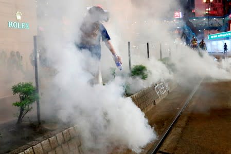 A woman tries to extinguish tear gas with water after a march to call for the passing of the proposed Hong Kong Human Rights and Democracy Act by the U.S. Congress in Hong Kong