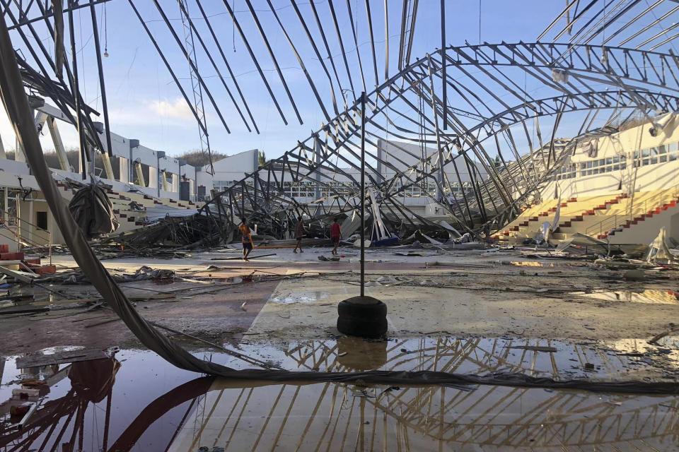 Residents walk inside a damaged sports complex building on Monday Dec. 20, 2021 that was used as an evacuation center when its roof collapsed due to Typhoon Rai at Siargao island in Surigao del Norte province, southern Philippines. The governor of a central Philippine province devastated by Typhoon Rai last week pleaded on radio Tuesday for the government to quickly send food and other aid, warning that without outside help, army troops and police forces would have to be deployed to prevent looting amid growing hunger. (AP Photo)