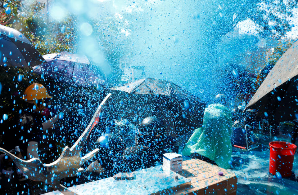 Protesters are sprayed with blue liquid from water cannon during clashes with police outside Hong Kong Polytechnic University (PolyU) in Hong Kong, China Nov. 17, 2019. (Photo: Thomas Peter/Reuters)