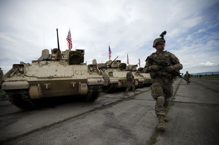 A member of the U.S. mechanized infantry company form 1st Brigade, 3rd Infantry Diivision walks past Bradley infantry fighting vehicles ahead an official opening ceremony of the joint U.S.-Georgian exercise Noble Partner 2015 at the Vaziani training area outside Tbilisi, Georgia, May 11, 2015. REUTERS/David Mdzinarishvili