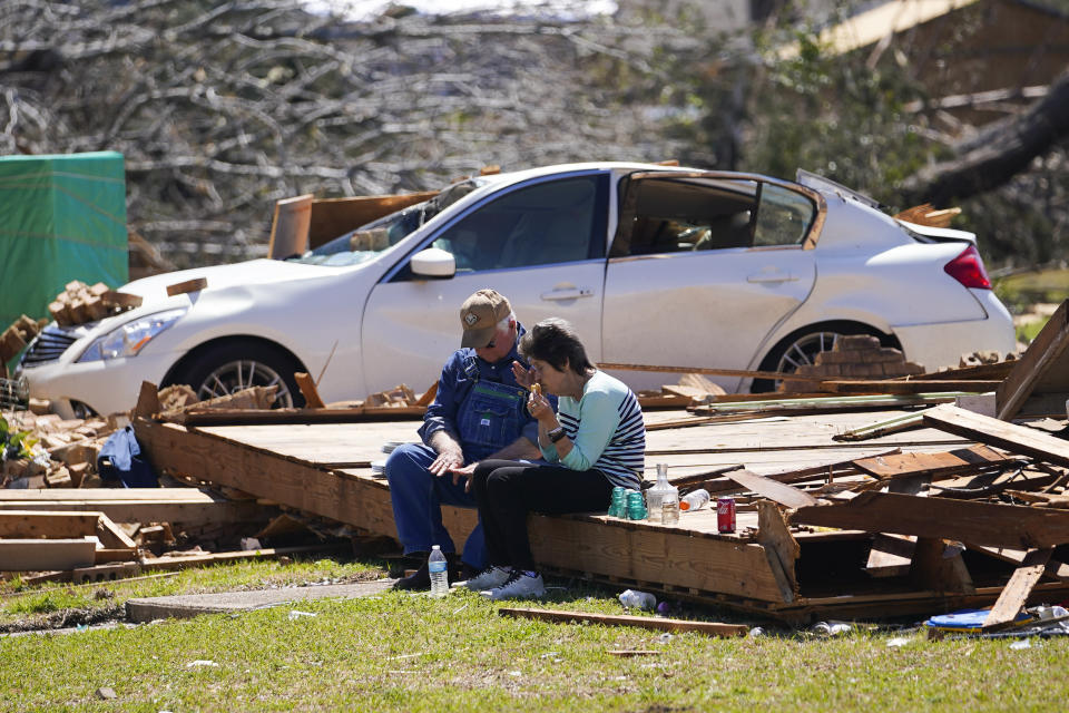 FILE - Charles Shields, left, sits with friend Robbie Diffey on the roof of Diffey's garage after a tornado destroyed her home, Monday, March 27, 2023, in Rolling Fork, Miss. President Joe Biden on Friday will visit a Mississippi town ravaged by a deadly tornado even as a new series of severe storms threatens to rip across the Midwest and South. (AP Photo/Julio Cortez, File)